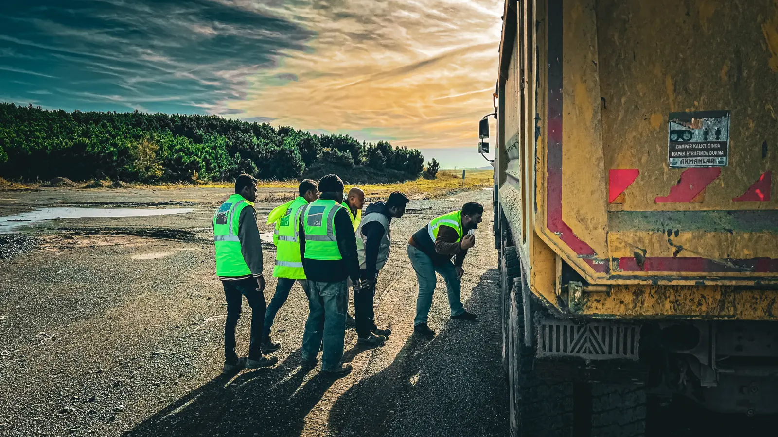 Yelekli ekip sahada kamyonu birlikte inceliyor; yol trafik güvenliği yönetim sistemi kapsamında araç kontrolü